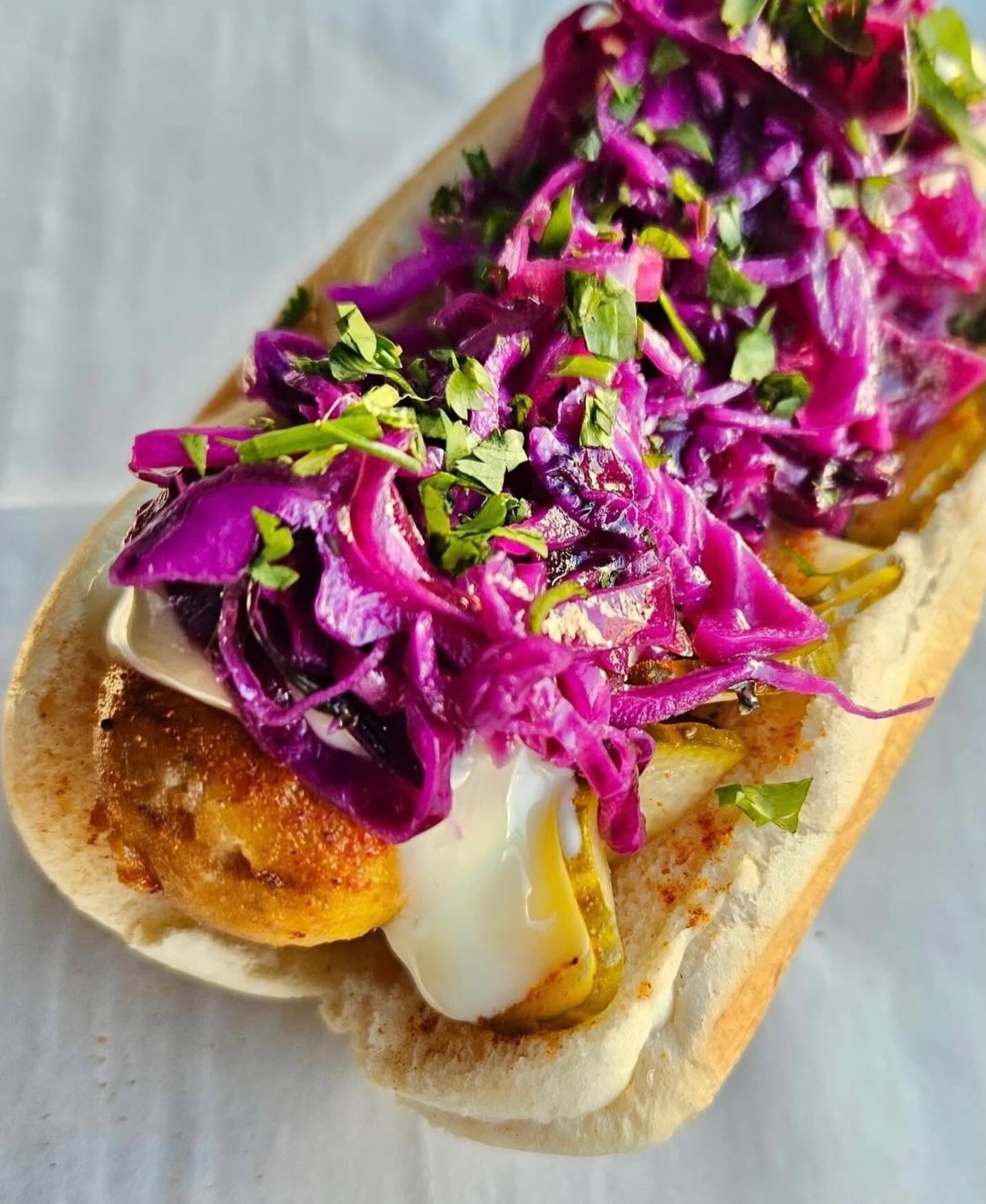 Sausage topped with purple cabbage slaw