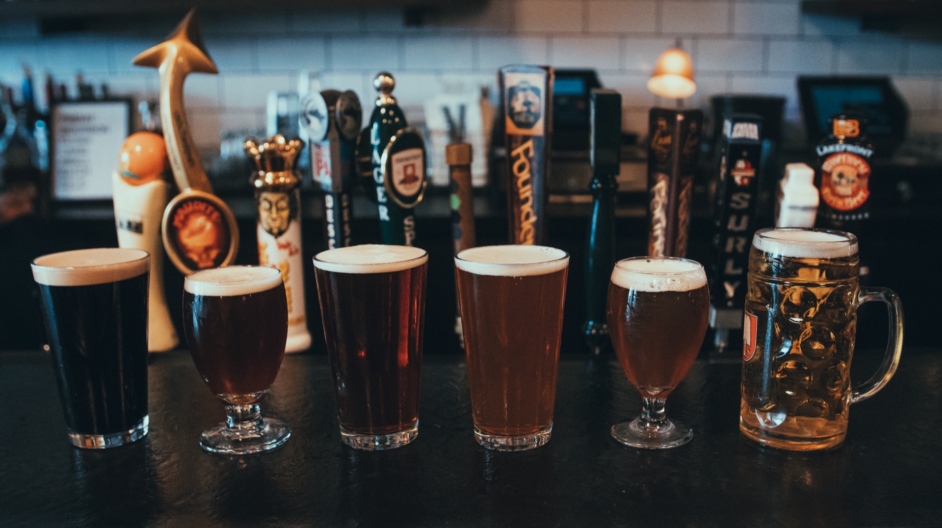 Six freshly-poured craft beers ranging from stout to lager on the bar