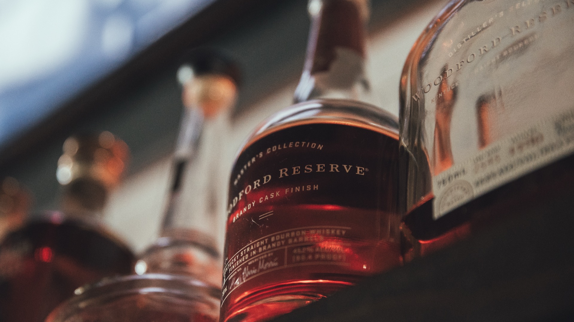 Woodford Reserve bourbon bottles glowing with warm amber backlighting